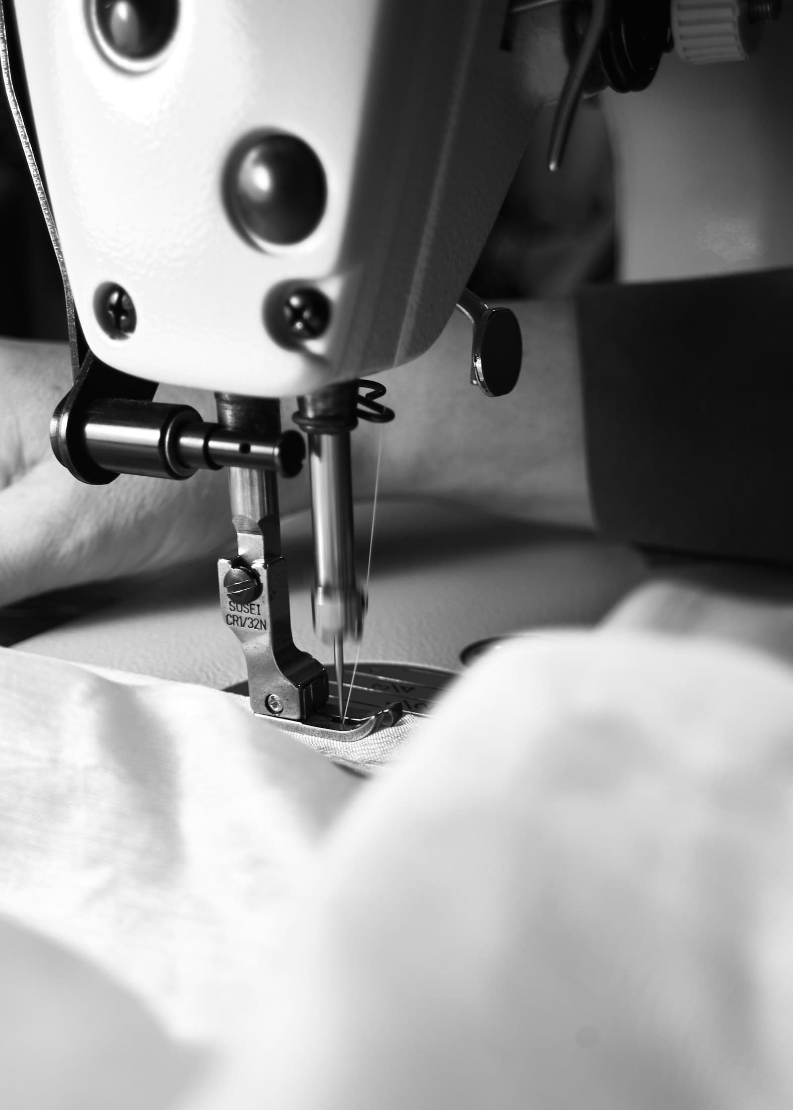 Close-up of a sewing machine needle on light fabric.