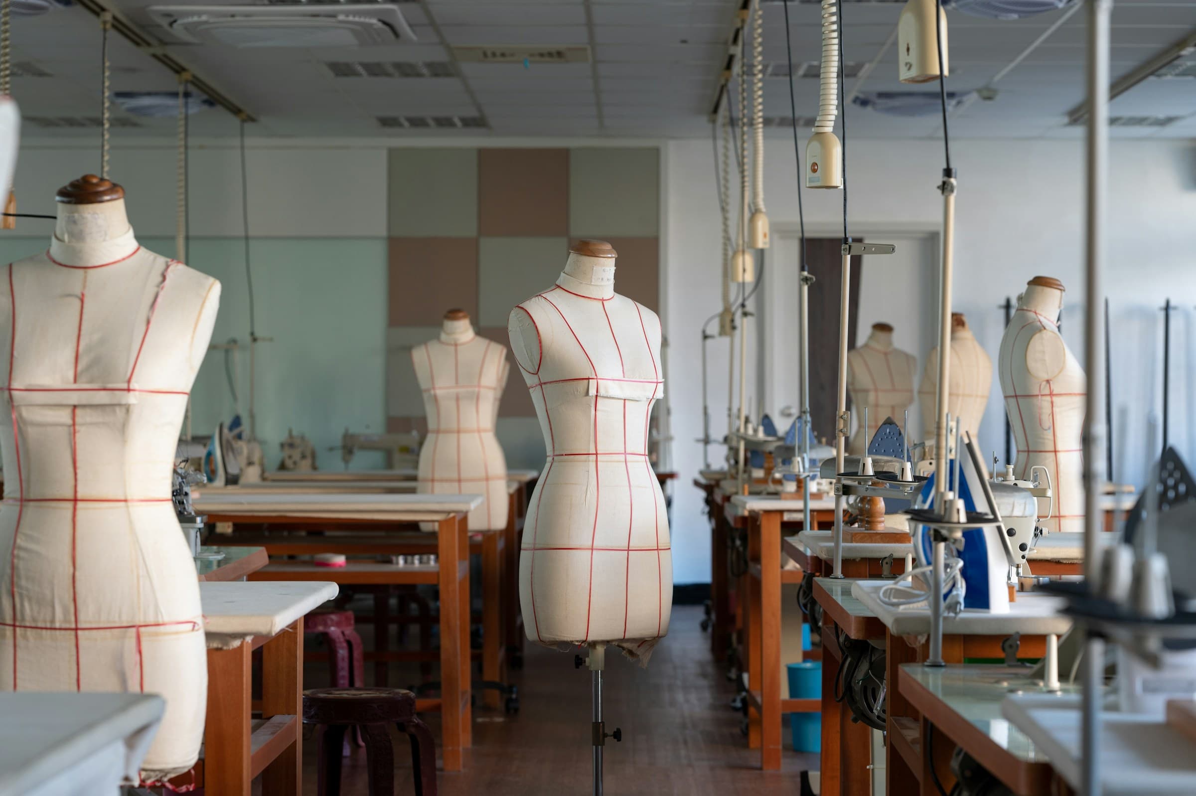 A garment workshop: tailor’s dress forms and sewing stations in a row.